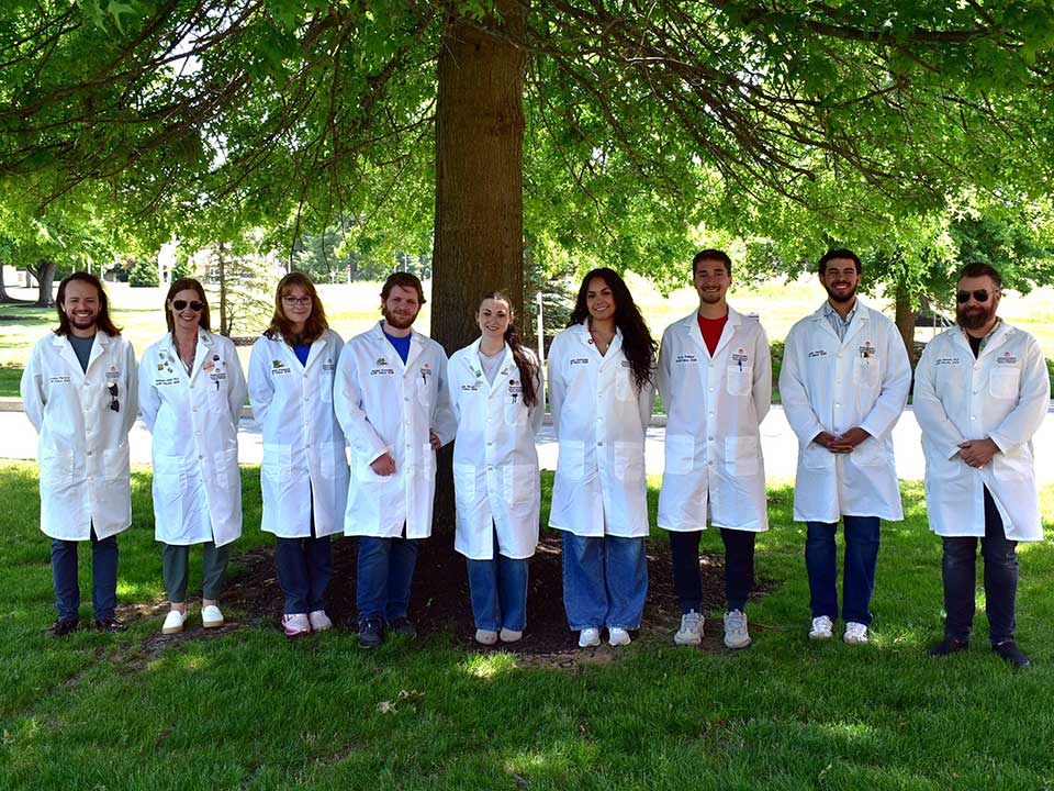 group of science students standing under trees on campus