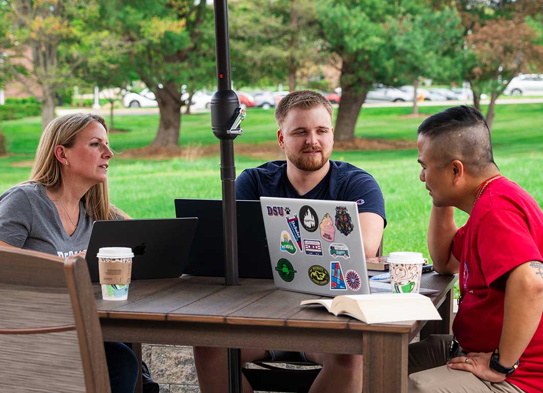 student with laptops at picnic table