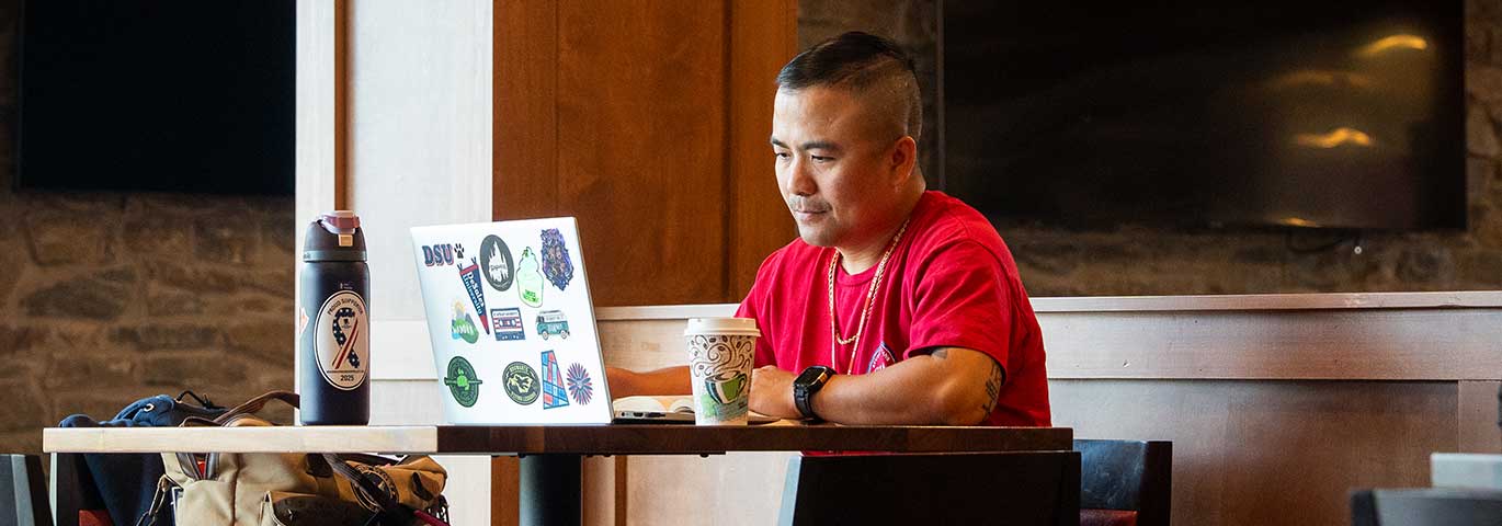 student with laptop at cafe