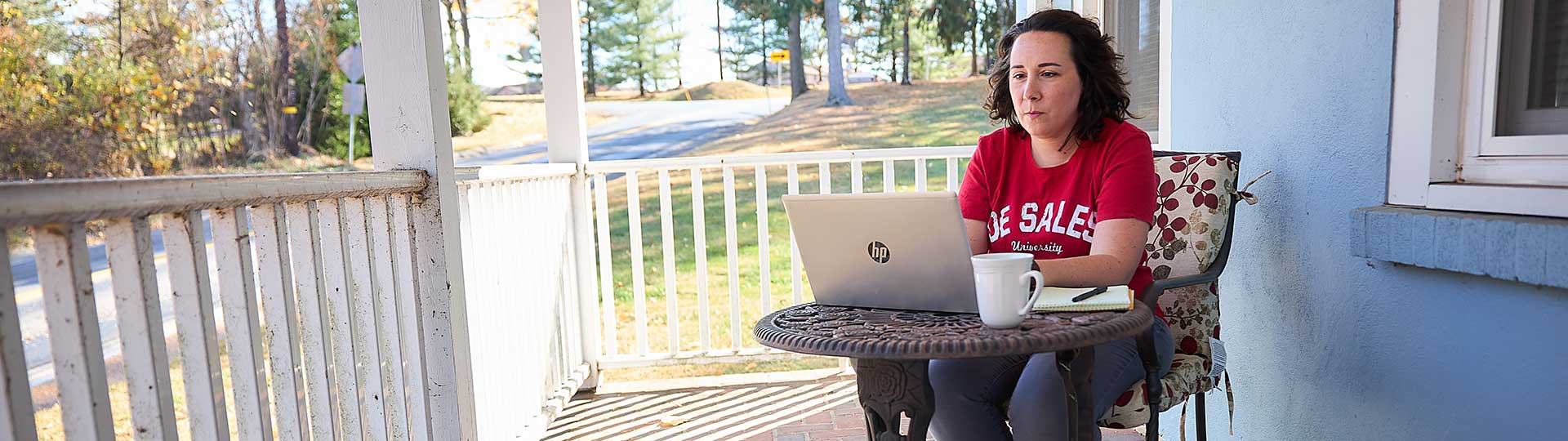 woman sitting on porch working on laptop