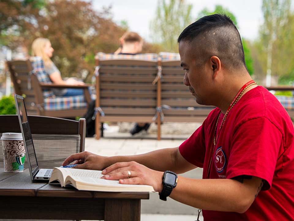 student with laptop at picnic table
