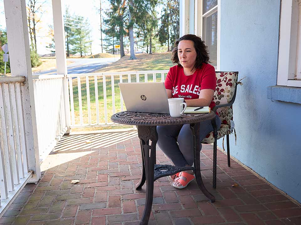 female student sitting on porch with laptop