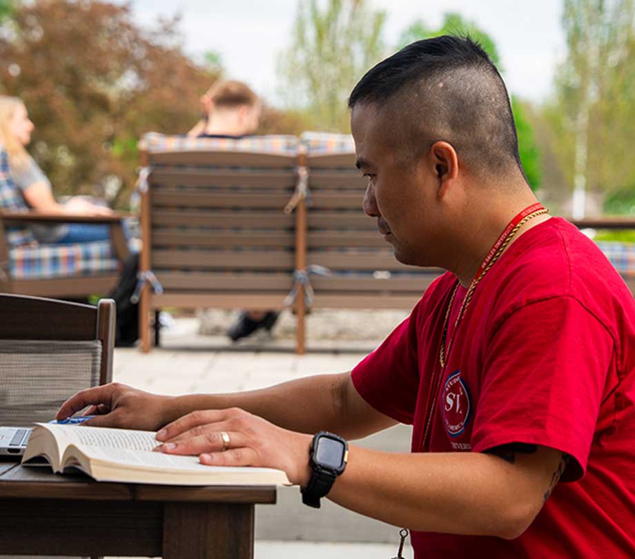 adult student doing work at picnic table