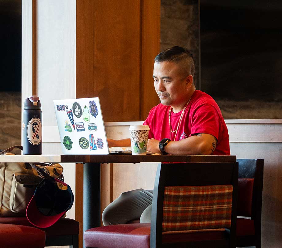 adult student working on laptop in cafe